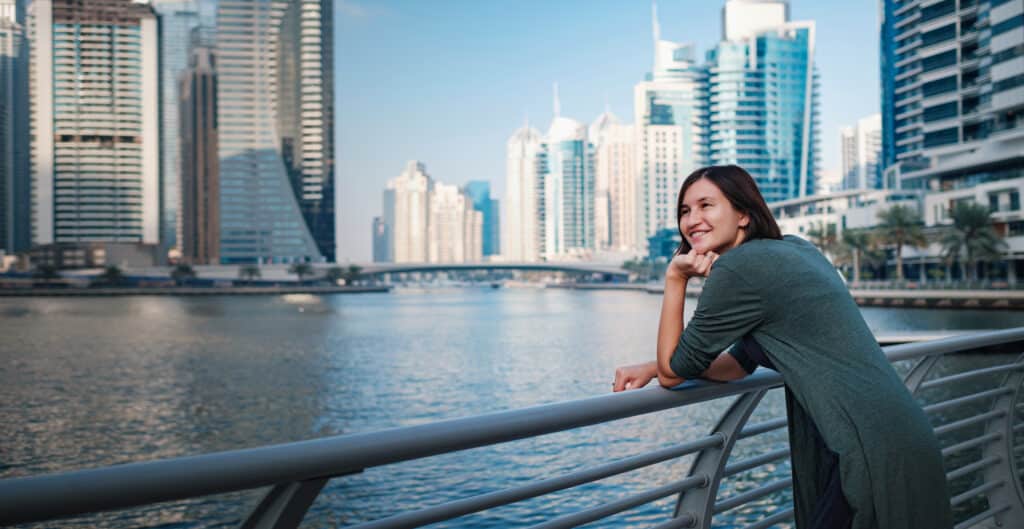 dubai urlaub kosten, lächelnde frau in der dubai marina, symbol für entspannenden und luxuriösen dubai-urlaub