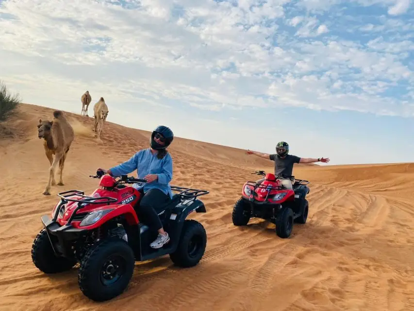 wüstensafari in dubai mit quad, touristen auf quad mit kamelen